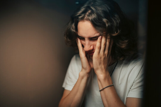Frustrated young man touching his face seen in bathroom mirror
