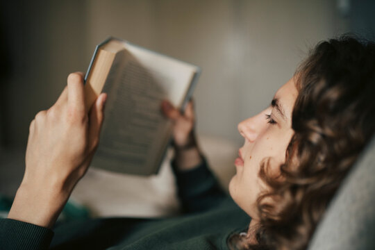 Close-up shot of young man reading book at home