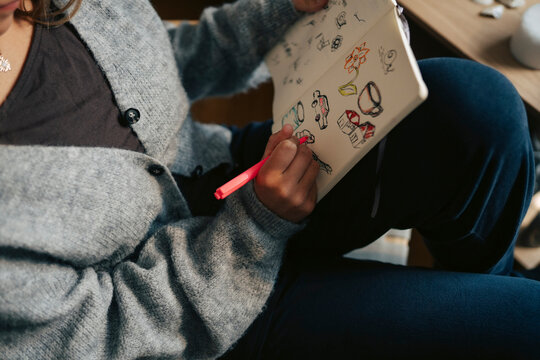 High angle view of teenage girl drawing doodles in notebook with pen