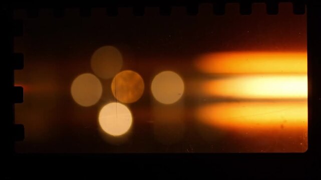 Three frames of 35mm film strip showing abstract orange light bokeh with bokeh horizontal motion