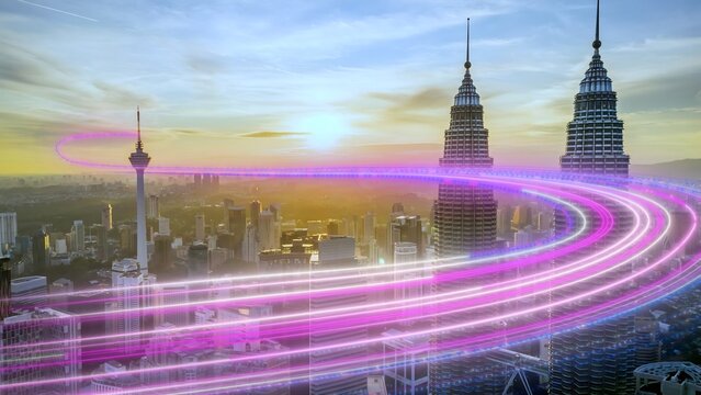 Aerial view of the Petronas Towers and KL Tower illuminated by vibrant purple light trails during a golden sunset over the skyline of Kuala Lumpur, Federal Territory of, Malaysia.