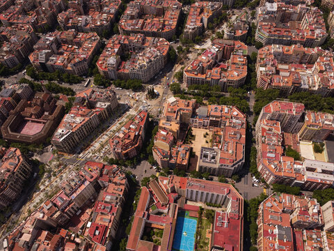 Aerial view of the dense urban grid of Barcelona, featuring characteristic Eixample district blocks with terracotta rooftops and tree-lined streets in Barcelona, Catalonia, Spain.