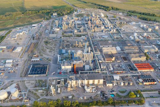 Aerial view of the industrial chemical plant with large storage tanks, complex pipeline networks, and surrounding agricultural fields in Bantzenheim, Grand Est, France.