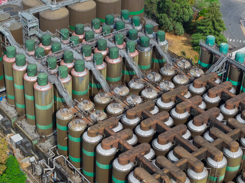 Aerial view of a beer brewery featuring numerous large industrial fermentation tanks connected by metal piping and walkways in the United Kingdom.