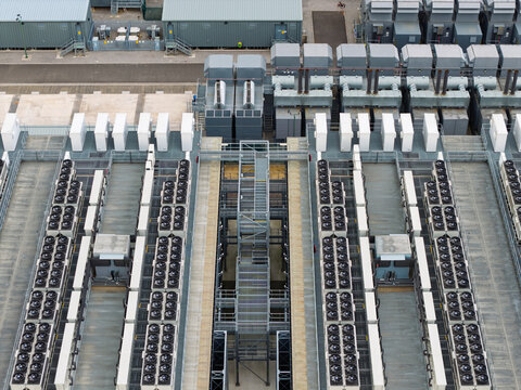 Aerial view of a large data center facility featuring rows of industrial cooling fans, HVAC units, and technical infrastructure in the United Kingdom.