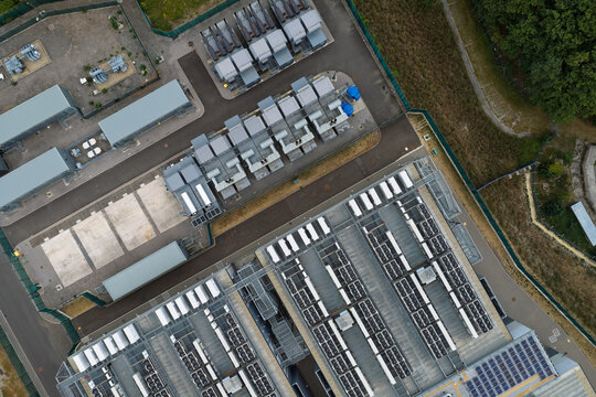 Aerial view of a modern data center featuring rows of cooling units, server infrastructure, and industrial equipment within a secure fenced perimeter in the United Kingdom.