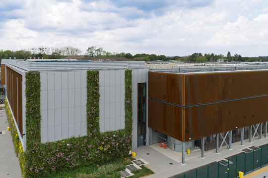 Aerial view of a modern data center building featuring a vibrant vertical green wall, sleek metal cladding, and contemporary architectural design in the United Kingdom.