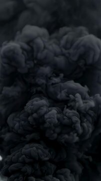 Thick black smoke billows into air. Abstract footage of explosion cloud. Concept of war and battlefield devastation. Cinematic dark background for military scene. Vertical video