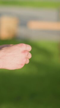 Close up of hands performing repetitive motion with fingers interlaced and moving in unison. background is consistently blurred green grass or outdoor setting suggesting open area like park