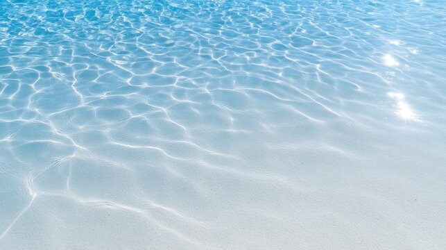 Clear blue water surface with ripples and sun reflections over sandy bottom