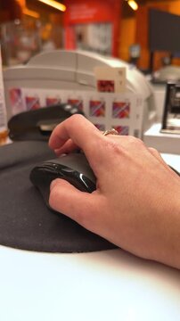 Hand clicking computer mouse on round black mousepad at office workstation desk, working environment, modern workflow, digital technology.