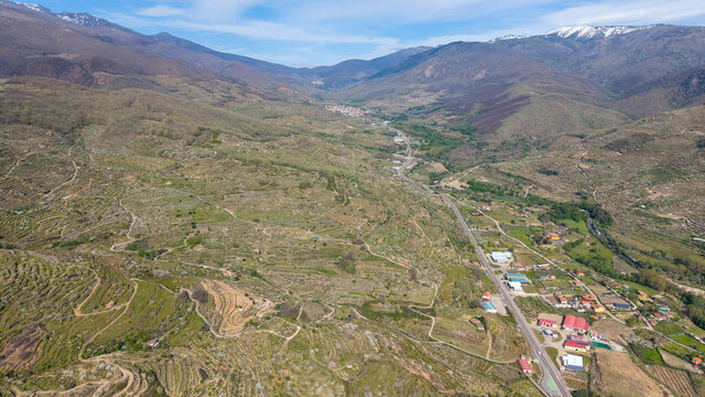 Aerial view of the Jerte Valley landscape featuring terraced hillsides, agricultural fields, and the town of Cabezuela del Valle, Extremadura, Spain.