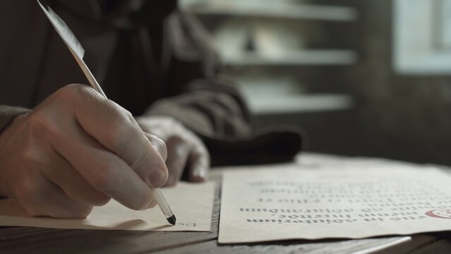 Hand of a monk copying Latin text from a psalm manuscript with a quill pen on parchment inside a medieval monastery scriptorium