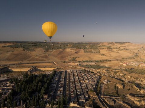 Aerial view of hot air balloons floating over the historic town and cemetery of Gravina in Puglia, Apulia, Italy.