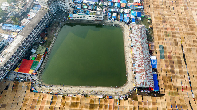 Aerial view of Charmonai pond surrounded by buildings, tents, and a large crowd of people in Charmonai, Barisal Division, Bangladesh.