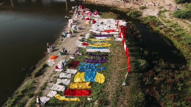 Aerial view of indian dhobi washing and drying colorful clothes on a river bank, yamuna river in agra. Traditional laundry system in a developing country