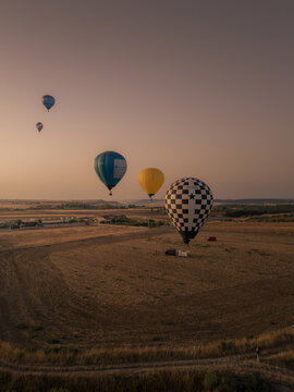 Aerial view of several hot air balloons drifting over the dry landscape during the golden hour in Gravina in Puglia, Apulia, Italy.
