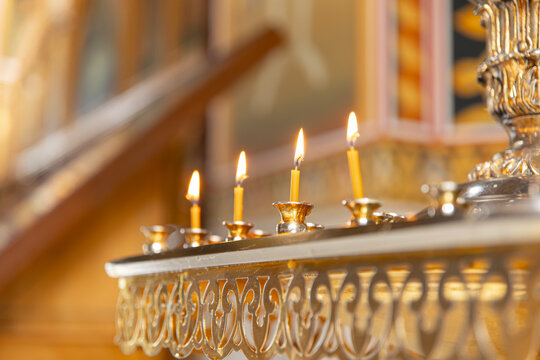 Wax candles in golden holder inside historic church, religious worship and spiritual faith concept