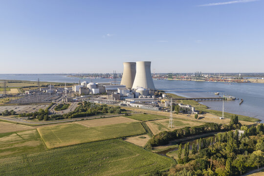 Aerial view of the Doel Nuclear Power Plant with cooling towers along the Scheldt river, surrounded by fields and industrial infrastructure in Beveren-Kruibeke-Zwijndrecht, Vlaanderen, Belgium.