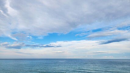 Fototapeta premium Dynamic layered cloudscape after a Mediterranean rainstorm, with stratocumulus, altostratus, ragged cumulus fractus, and distant congestus clouds over the coastal horizon