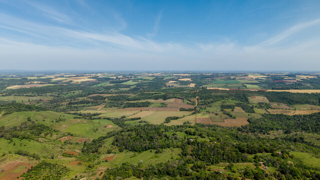 Aerial view of rolling green hills, agricultural fields, and patches of forest in the countryside of Nueva Alborada, Itapua Department, Paraguay.