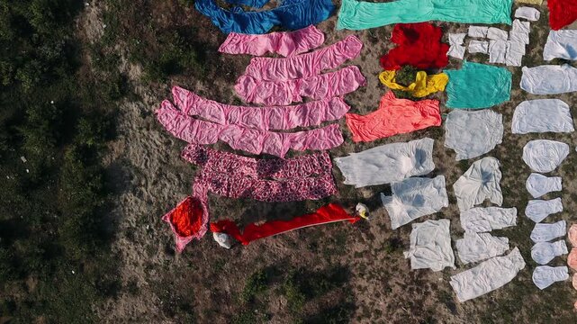 Aerial view of a traditional indian laundry, with a worker drying clothes on the ground in rural india