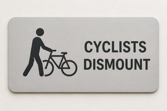 A grey rectangular sign with a silhouette of a person walking a bicycle and the text CYCLISTS DISMOUNT.