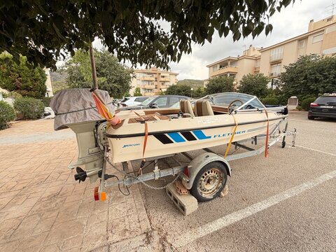 Mallorca, spain, august 30, 2026, old fletcher motorboat on a trailer parked under a tree in calvia. Waiting for restoration or transport, depicting summer lifestyle