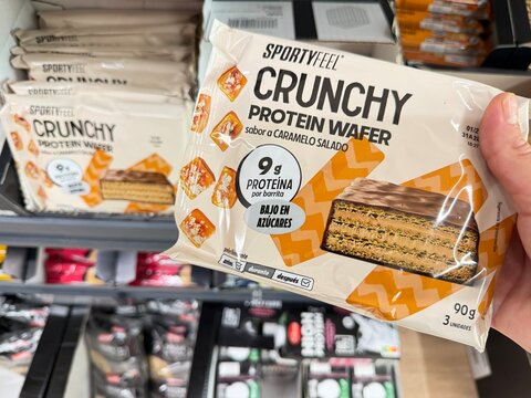 Mallorca, spain, august 30, 2026, hand holding sportyfeel crunchy protein wafer with salted caramel flavor and 9g protein in a supermarket in spain