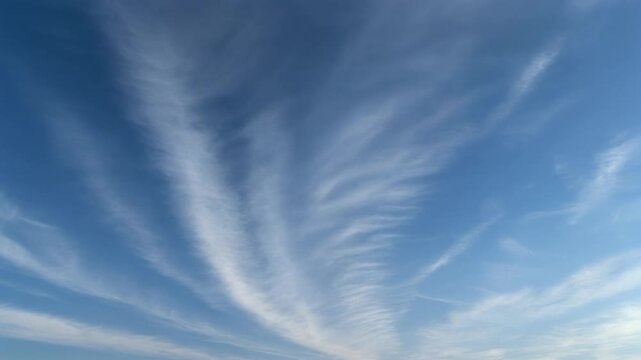 Wispy cirrus clouds stretch across a bright blue sky on a clear sunny day.