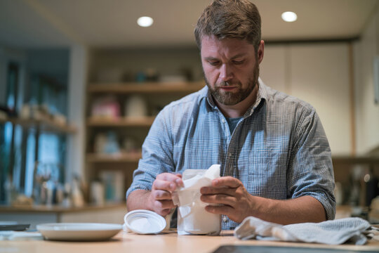 A serious man unwraps a white container, highlighting focus and dedication required in obtaining precise information from products or ingredients.