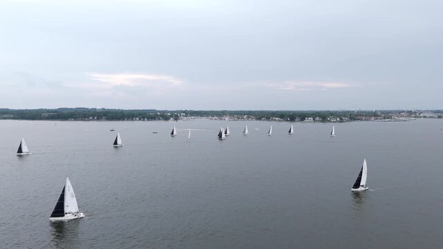 Fleet Of Sailboats Racing In The Calm Water Of River On An Overcast Day. - aerial shot