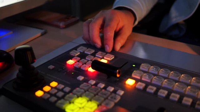 Close-up of a television operator using a professional broadcast control console during live studio production