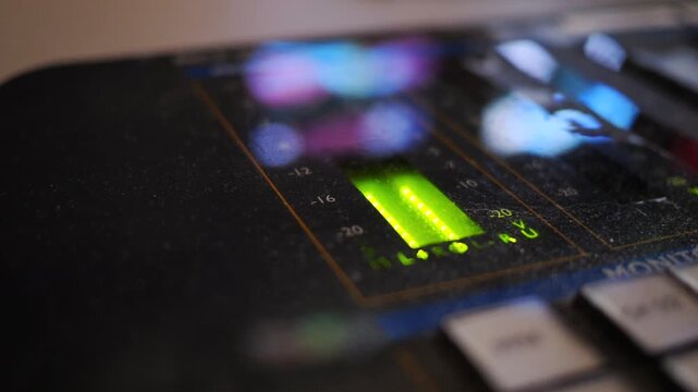 Close-up view of a professional television production control console with illuminated controls and digital level indicators