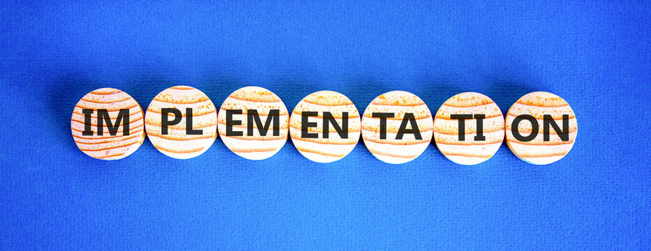 Implementation word symbol. Concept word Implementation on beautiful wooden circles. Beautiful blue background. Business implementation word concept. Copy space.