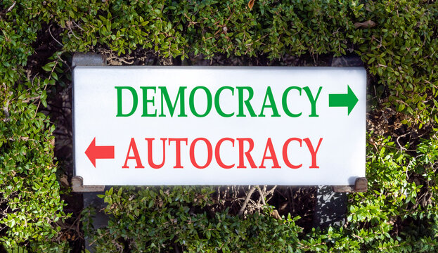 Democracy or autocracy words symbol. Concept words Democracy Autocracy on beautiful white sign plate. Beautiful green leaf background. Business democracy autocracy concept. Copy space
