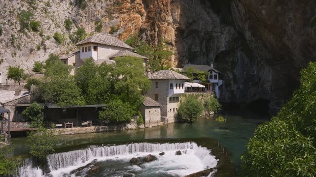 Blagaj Tekke monastery beside the Buna River and waterfall beneath limestone cliffs in Bosnia and Herzegovina, handheld static medium