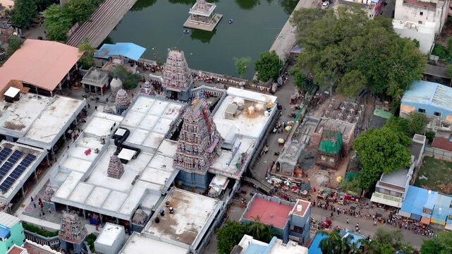 Cinematic aerial view of Vadapalani Murugan Temple, Chennai, showcasing the colorful temple towers, surrounding temple complex, sacred water tank, busy streets, and dense urban development.