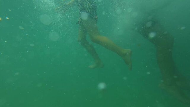 Two Boys Swimming and Playing in the Sea Water near Sandy Wild Beach