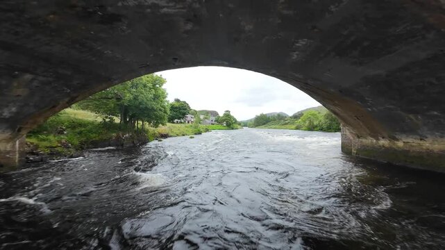 FPV drone flight following a typical Scottish river. Shot in Poolewe in the Highlands of Scotland the flight follows the course of the river after flying under a road bridge.
