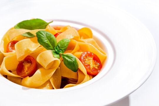 Italian food: pasta with tomato and basil. Food minimalism vibrant presentation Premium vegan diet nutrition approach. Ultimate carbohydrate comfort food served on clean plate.