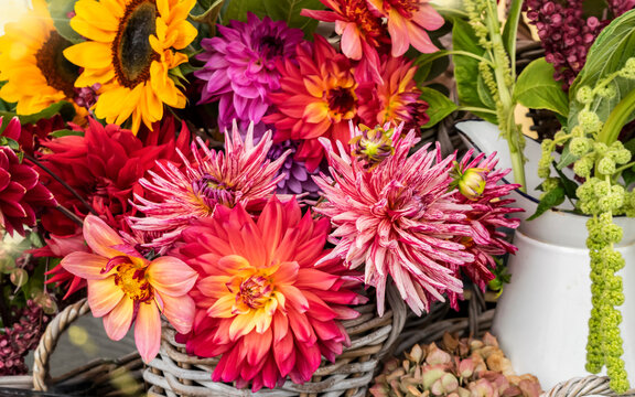 Autumn sunny bouquet of dahlias and sunflowers in a wicker basket, selective focus
