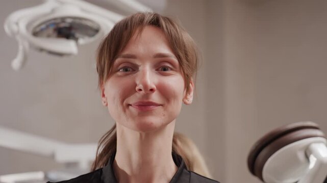 Close up of dental professional wearing clear protective eyewear in orthodontic clinic. person adjusts face shield while standing near modern medical equipment with soft lighting and neutral
