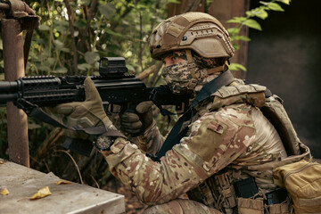 Obraz premium Armed military operator aiming a rifle during a combat patrol mission.