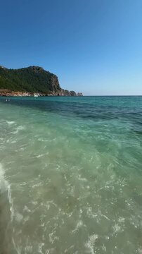 Azure waves crashing on Cleopatra Beach in Alanya, Turkey, with the peninsula and ancient Ic Kale fortress in the background