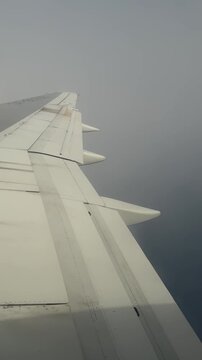 Passenger window view of an airplane wing flying through heavy clouds on a overcast day