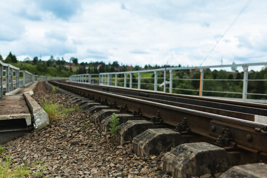 Close up view of metal railway tracks and concrete sleepers on a bridge.
