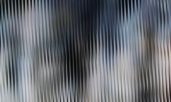 Futuristic silver ribbed glass texture background with subtle blue undertone featuring vertical fluted pattern for modern architectural backdrop design.