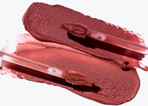 Two lipstick smears with applicators on white
