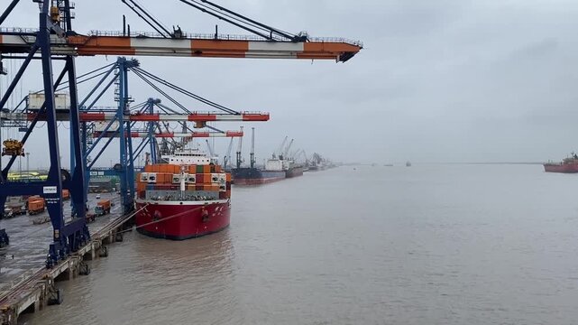 Container crane and port equipment viewed across the harbor in soft, hazy weather.